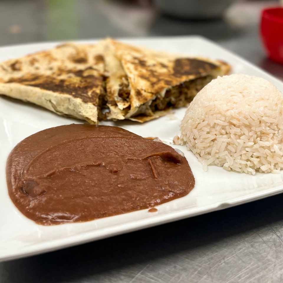 White plate featuring folded grilled quesadillas, refried beans, and a mound of white rice on a restaurant counter.
