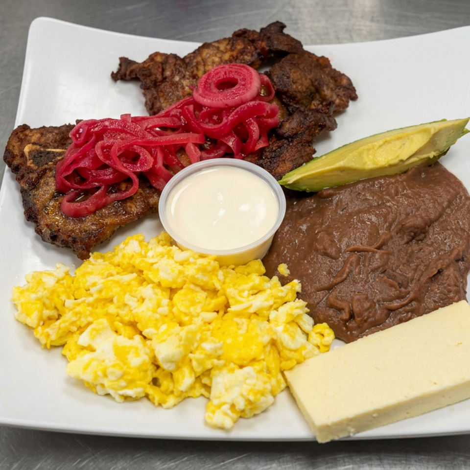 Breakfast plate with scrambled eggs, refried beans, fried meat, pickled onions, avocado, cream sauce, and cheese.